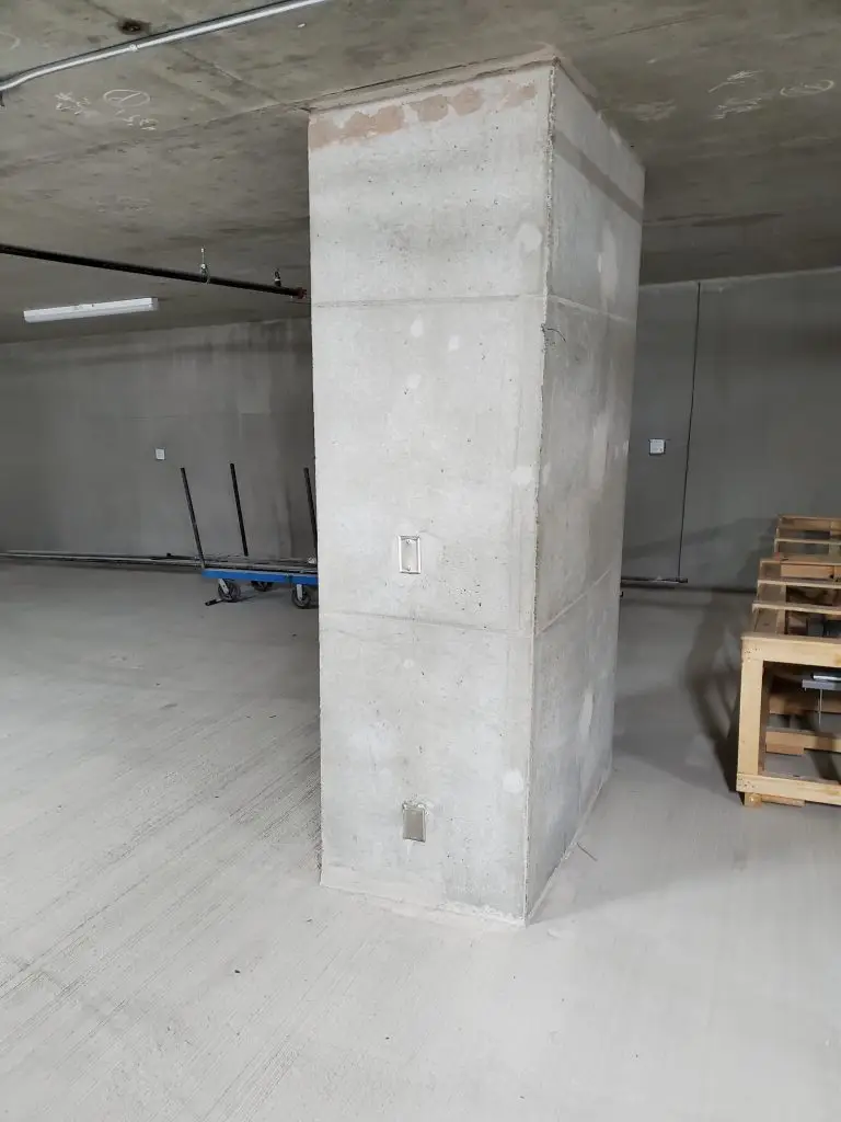 Certified technician safely removing a large paper wasp nest from the corner eave of a downtown Seattle parking garage entrance.